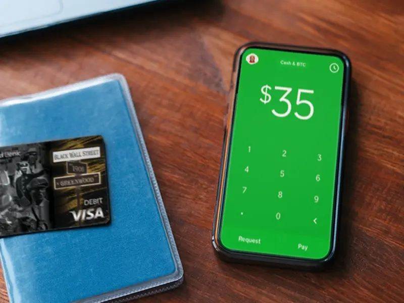 A phone with a credit card on it next to a wallet.