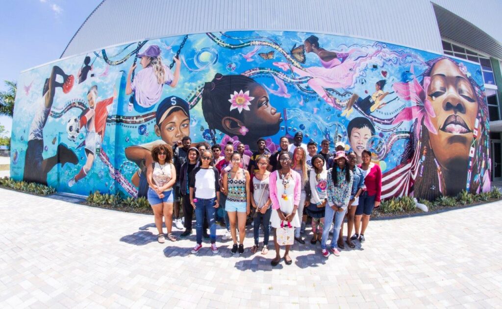 A group of people standing in front of a mural.