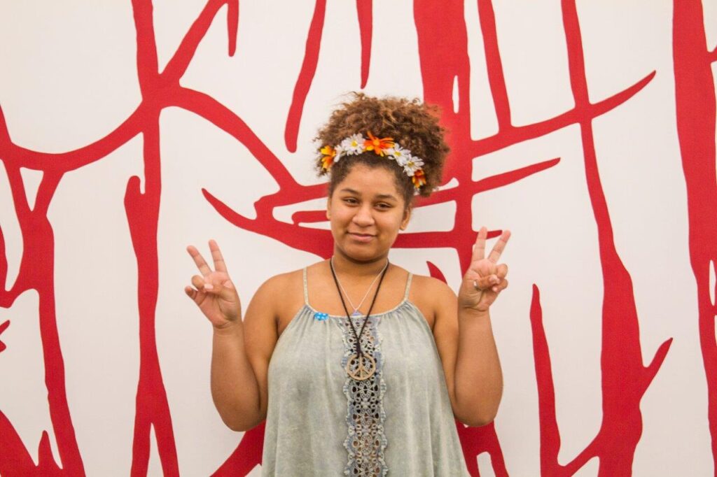 A young woman posing for a photo in front of a red wall.