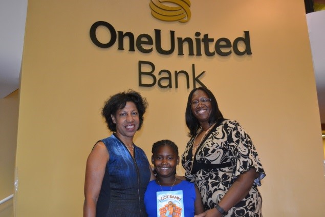 Three women standing in front of a one united bank sign.