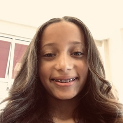 A young girl with braces smiles for the camera.