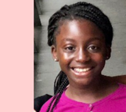 A young girl with braids smiles for the camera.