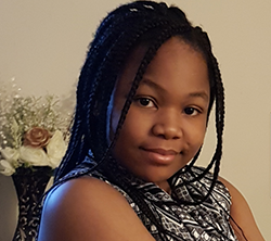 A young girl with braided hair is posing for a photo.