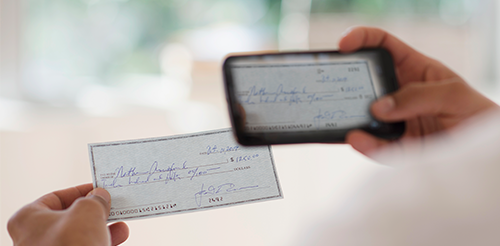 A person holding a check in front of a camera.