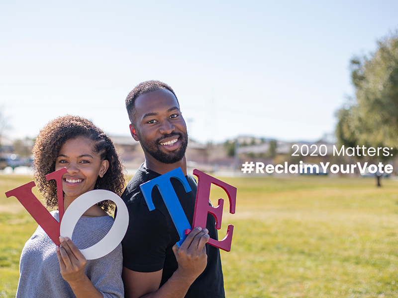 A couple holding signs with the words 2020 matters reclaim your vote.