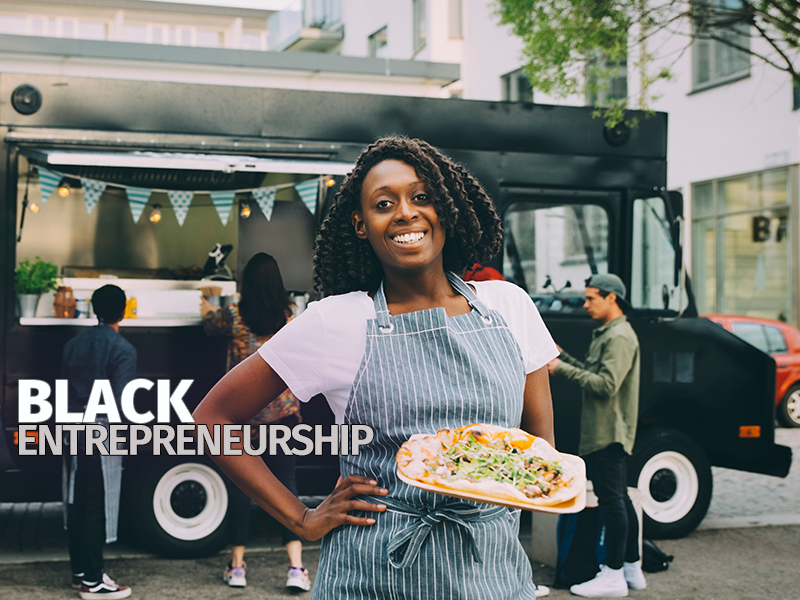 A woman holding a food truck with the words black entrepreneurship.