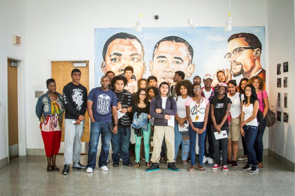A group of people posing in front of a mural.