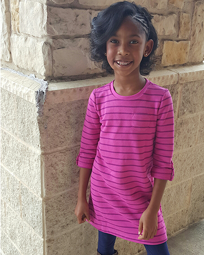 A little girl wearing a pink striped dress.