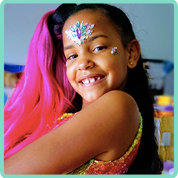 A girl with colorful hair and face paint smiles for the camera.