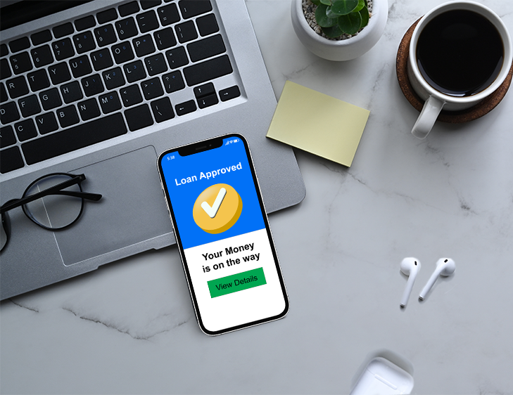 A smartphone on top of a laptop that says "Loan Approved"