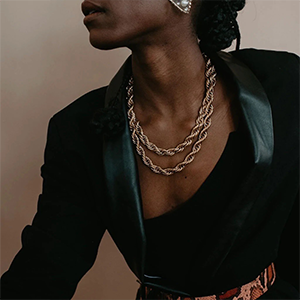 A black woman wearing a black jacket and gold chain necklace.