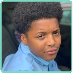 A boy in a blue shirt is sitting in a car.