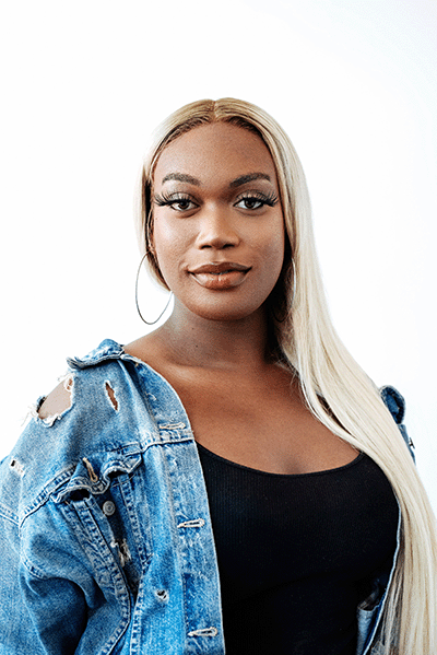 A black woman in a denim jacket posing for a photo.