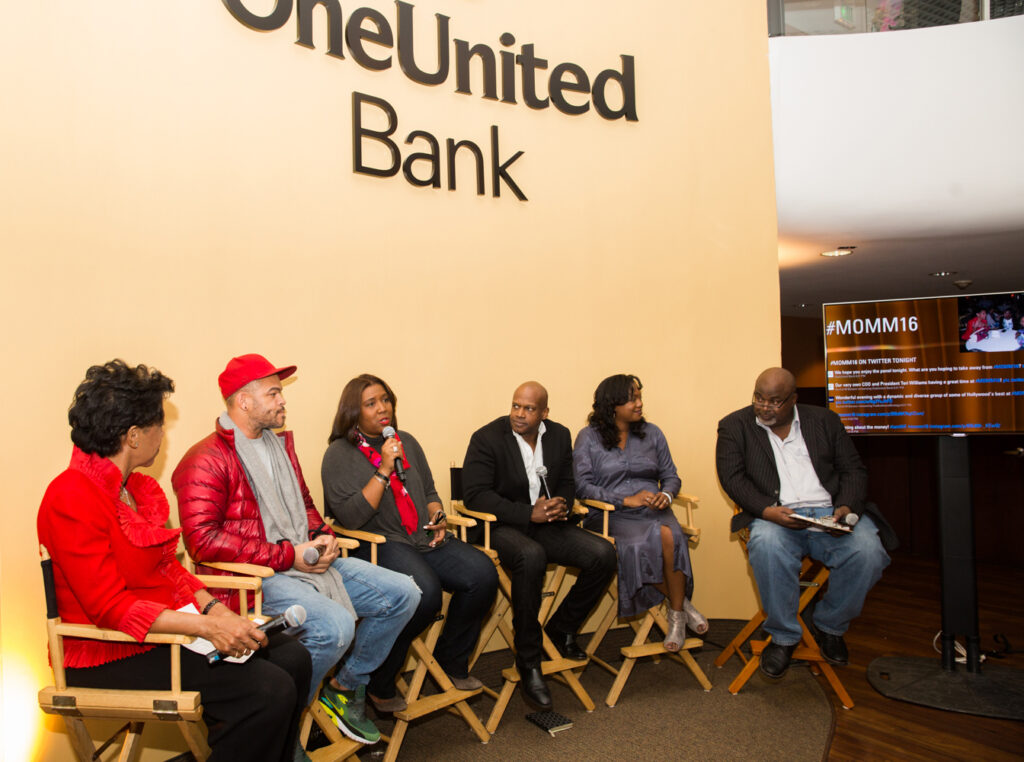 A group of people sitting in chairs in front of a one united bank sign.