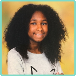 A girl with curly hair is smiling in front of a yellow background.