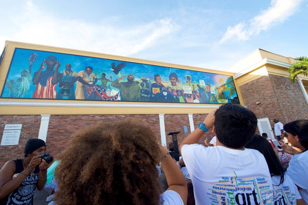 A group of people are taking pictures of a mural on the side of a building.