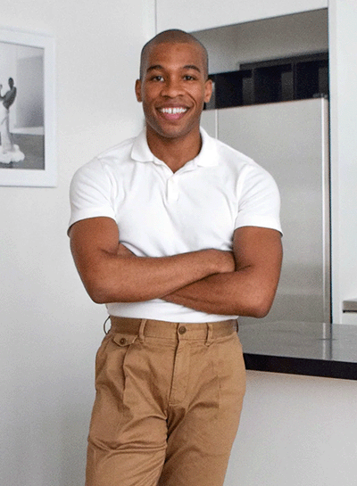 A man in a white shirt and khaki pants standing in a kitchen.