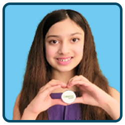 A young girl holding a heart shaped cookie.