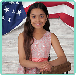 A young girl posing in front of an american flag.