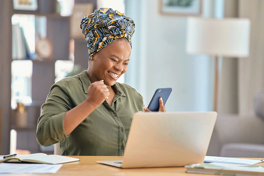 A woman is sitting at a desk with a laptop and a turban on her head.