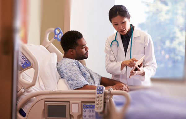 A doctor is talking to a patient in a hospital bed.