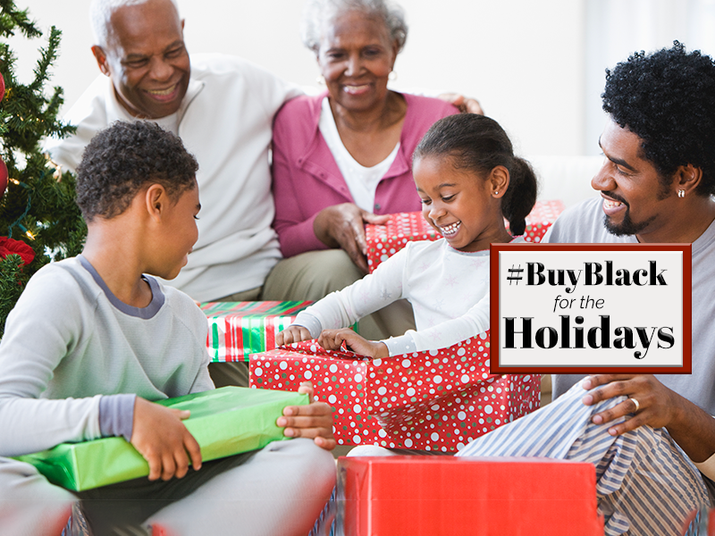 A family is sitting in front of a christmas tree with gifts and the text buy black holidays.