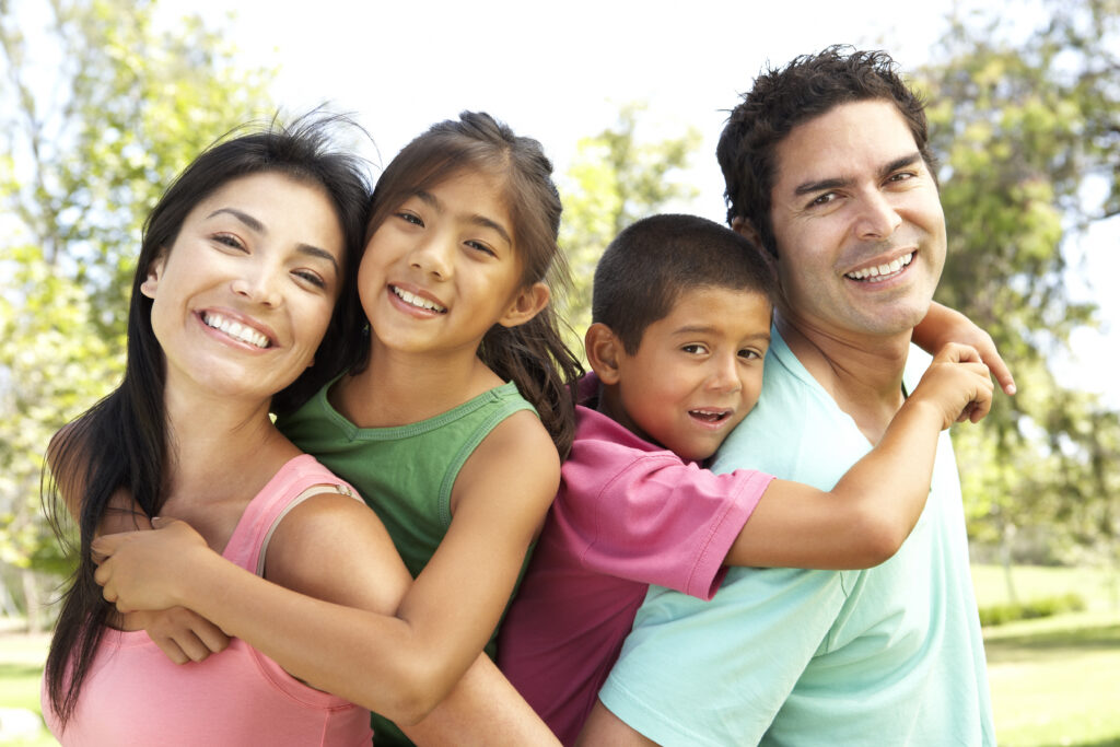 A family is smiling in a park.