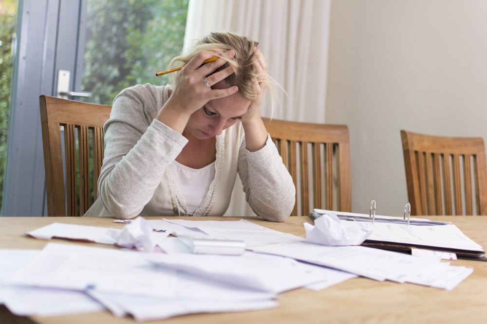 A woman sitting at a table with piles of papers.