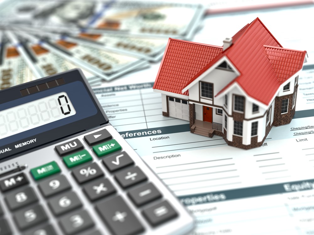 A house model and calculator on top of a pile of money.