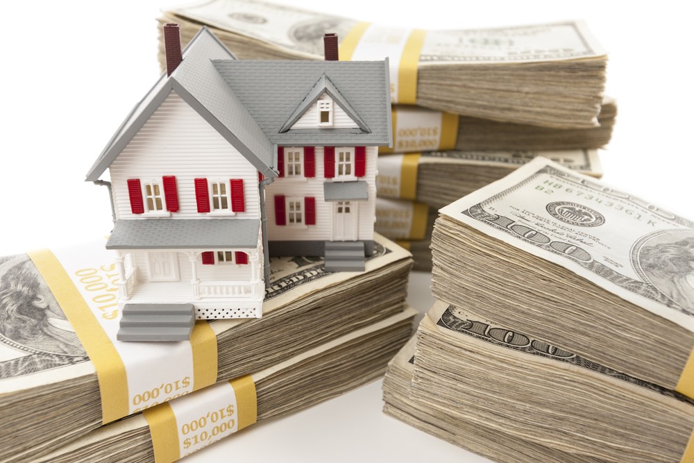 A model house on top of stacks of money.