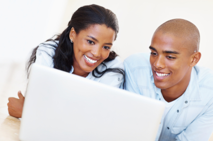 A man and woman are looking at a laptop.