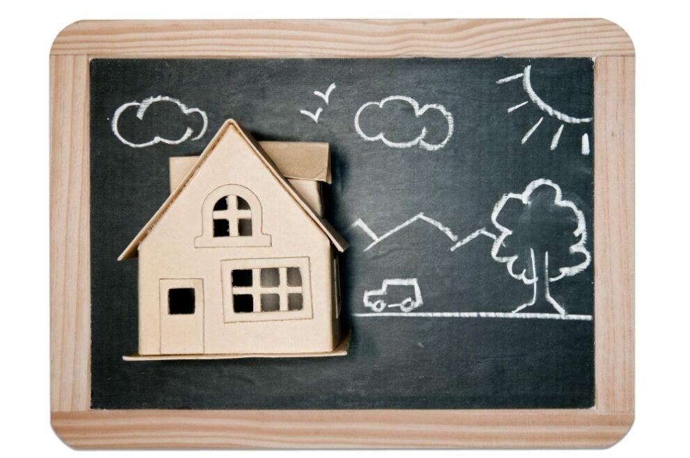 A cardboard house and a yard drawn on a chalkboard