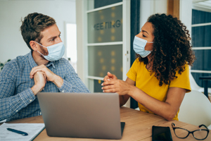 Two people collaborating with COVID masks on