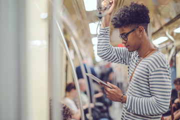 man standing on a train looking at his phone