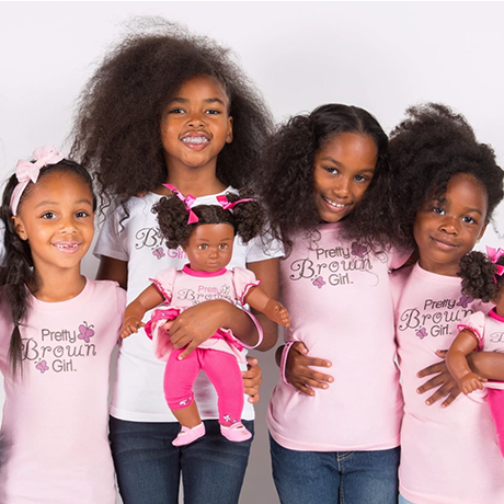 A group of girls in pink t - shirts posing with their dolls.