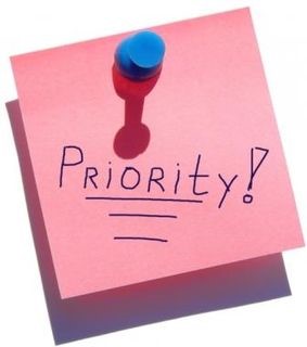 A pink post it note with the word priority on it.