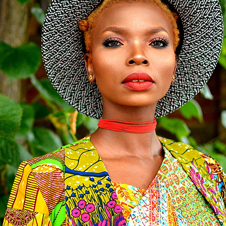 A young african woman in a colorful dress and hat.