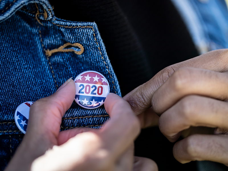 A person is putting a 2020 pin on their jacket.