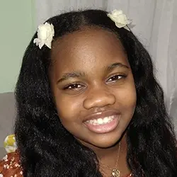 A young girl with long hair smiling for the camera.