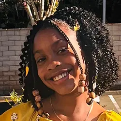 A young girl in a yellow dress smiling.