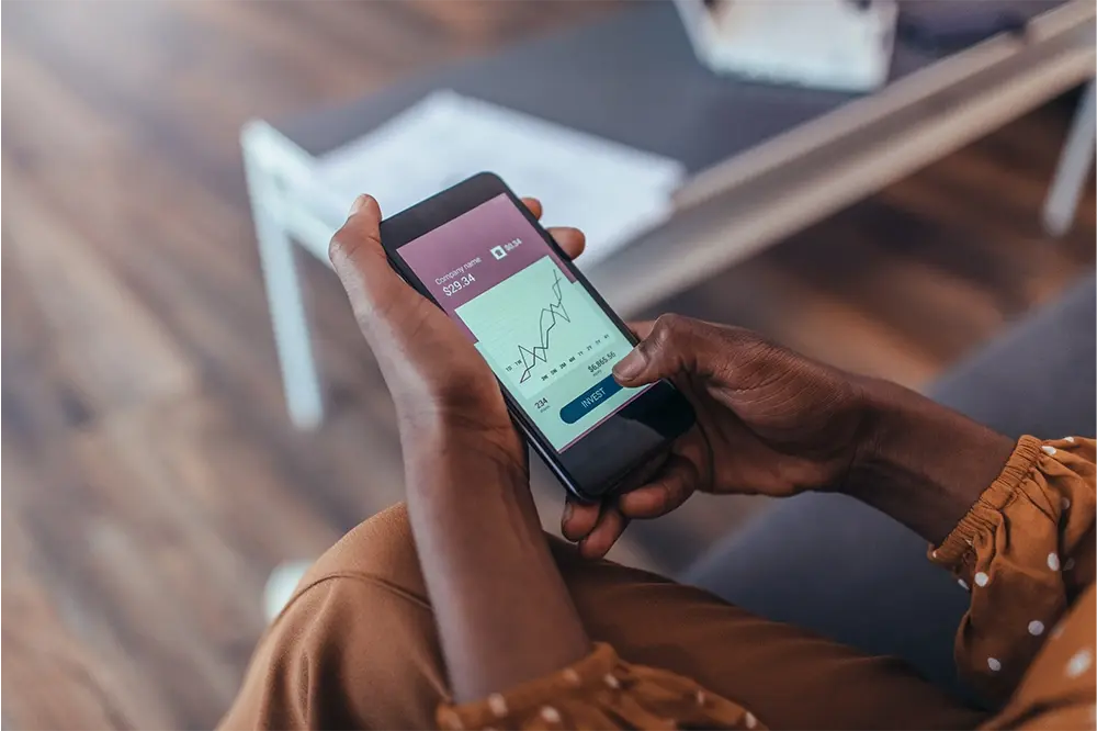 A woman holding a smartphone with a graph on it.