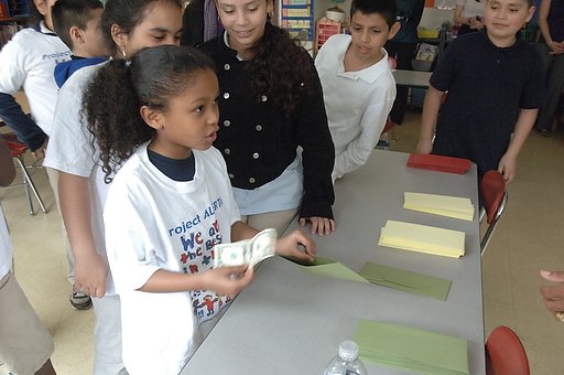 A group of children standing around a table with money.