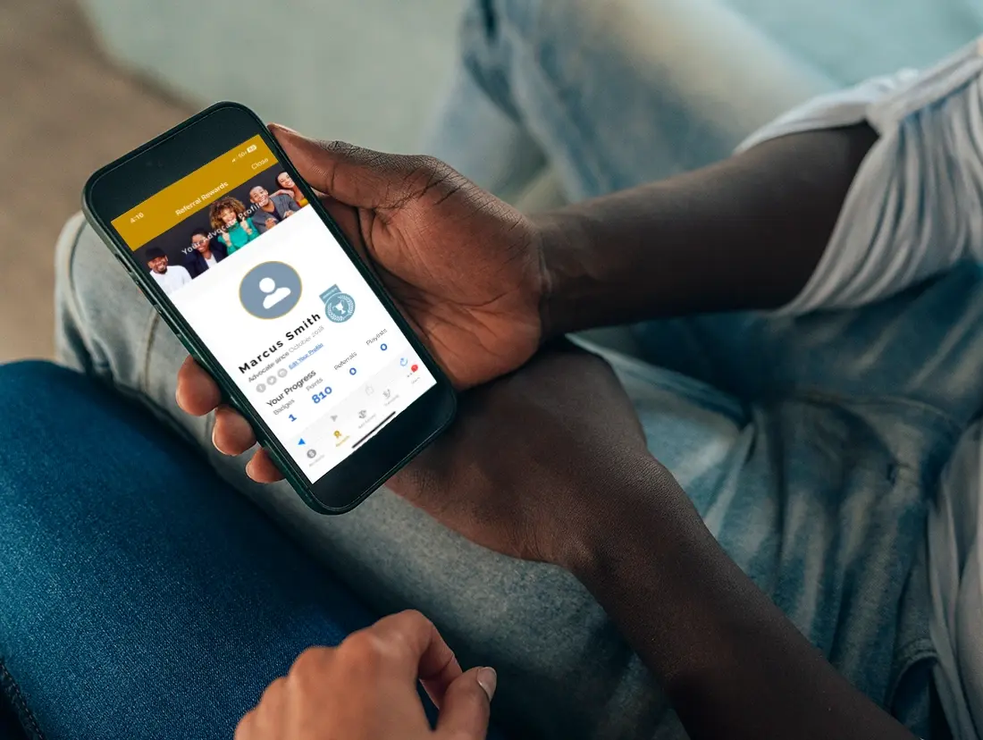 A person sitting on a couch holding a phone with a social media app on it.