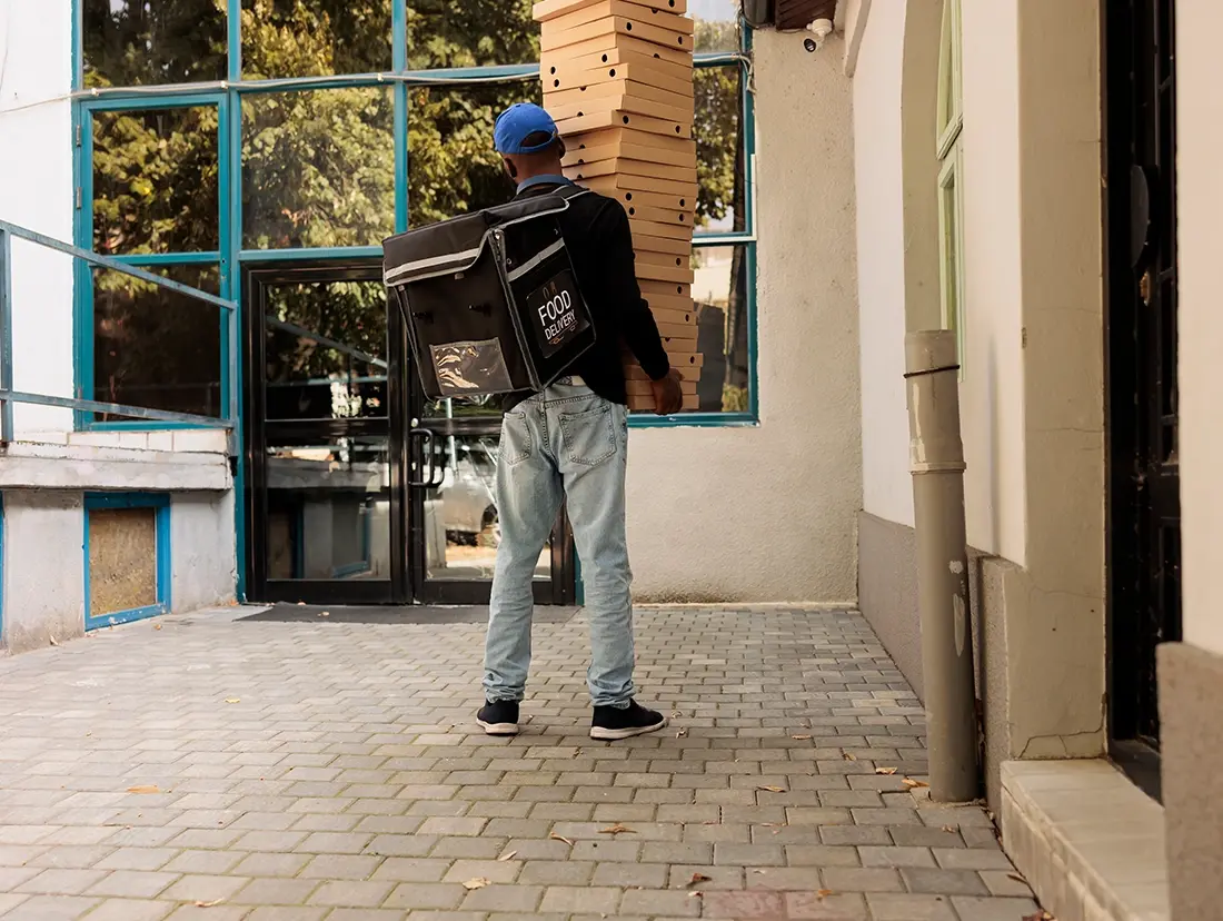 A man carrying a pizza box on a sidewalk.