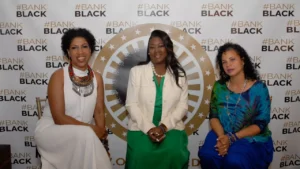 Three women posing in front of a bank black sign.