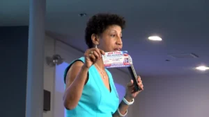 A woman holding up a voter registration card in front of a microphone.