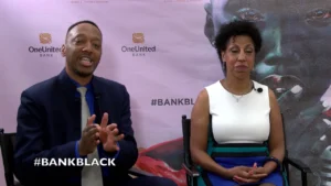 A man and woman sitting in front of a wall with the words bank black.