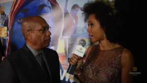 A man and woman talking to a microphone on a red carpet.