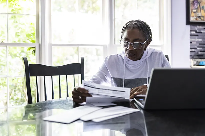 An older woman using a laptop at a table.