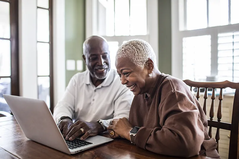 An older couple using a laptop at home.